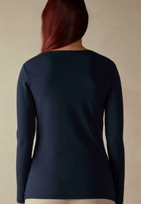 Marineblaues Langarmoberteil mit rundem Halsausschnitt, glattem Stoff und taillierter Silhouette, mit geradem Saum und ohne sichtbare Details.