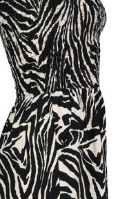 Black and cream zebra-patterned dress with a smocked bodice, featuring a straight silhouette and side pocket detail. Soft, textured fabric.
