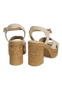 Sandales en suède beige à plateforme avec de larges lanières croisées et un talon épais texturé en liège. Bride de cheville ajustable avec matériel doré.