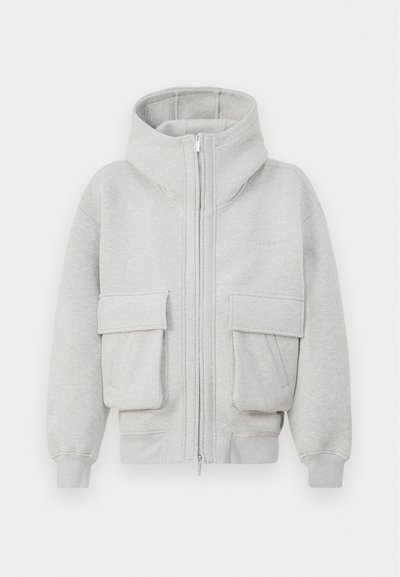 Haut de sweat à capuche gris zippé en tissu doux, avec un col haut, deux grandes poches avant et des poignets côtelés aux manches et à l'ourlet.
