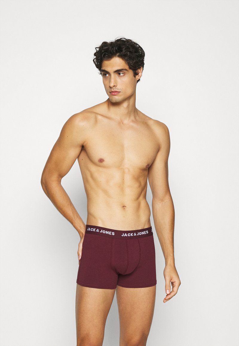Boxer shorts bordeaux avec une ceinture élastique noire portant le logo blanc "JACK & JONES". Le tissu semble doux avec une texture lisse.