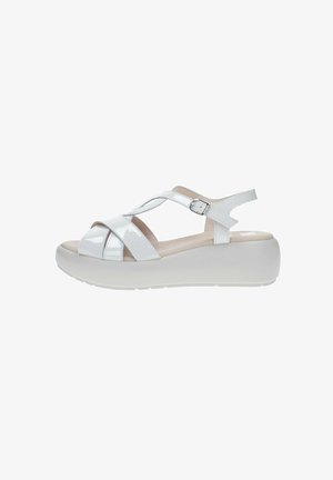Sandalias de charol blanco con diseño de tiras cruzadas, hebilla ajustable y una suela de plataforma gruesa blanca para mayor altura y comodidad.