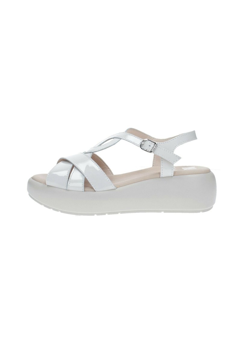 Sandalias de charol blanco con diseño de tiras cruzadas, hebilla ajustable y una suela de plataforma gruesa blanca para mayor altura y comodidad.