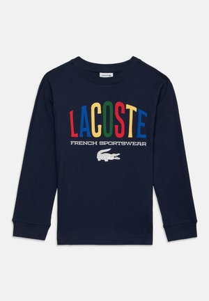 Marineblå langærmet skjorte med flerfarvet "LACOSTE" tekst, hvid "French Sportswear" tagline og hvid krokodillelogo foran.