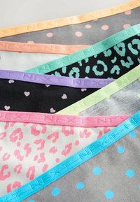 Pile de sous-vêtements colorés à motifs avec des bandes élastiques à la taille dans divers imprimés incluant des pois, des cœurs et des taches de léopard.