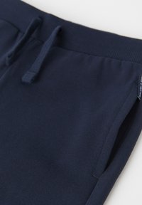 Marineblaue Jogginghosen mit einem gerippten Bund, Kordelzug und Seitentaschen. Weicher, strukturierter Stoff mit lockerem Schnitt.