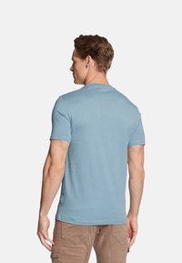 T-shirt azzurro chiaro a maniche corte, colletto tondo, materiale misto cotone, texture liscia, design aderente, cuciture visibili sulle maniche e sull'orlo.