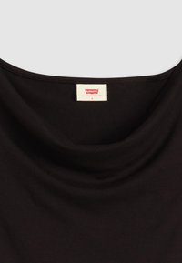 Svart topp med rundad halsringning och draperad nacke, tillverkad av mjukt tyg. Levi's etikett sydd vid nacken, storlek små, med en diskret design.