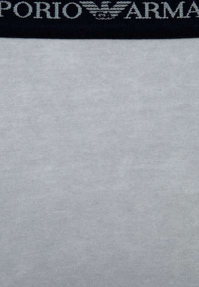 Lys grå stoff med en jevn tekstur, med en mørk marineblå linning som viser "Emporio Armani" i lys grå skrift.
