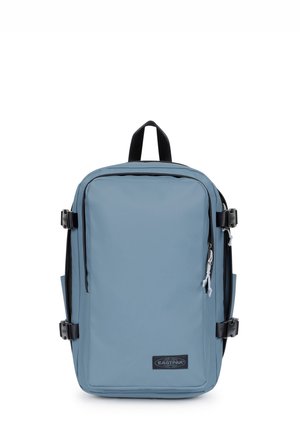 Sac à dos rectangulaire bleu avec poignée noire, boucles latérales noires et poche zippée à l’avant sur fond blanc.