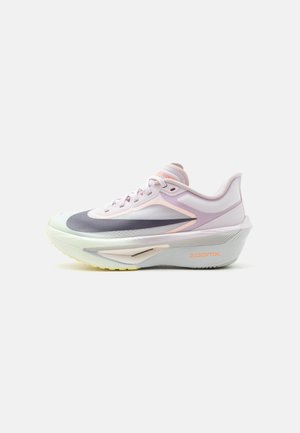 Zapatilla de correr blanca y rosa claro con detalles en gris y durazno, suela gruesa acolchada etiquetada "ZOOMX" y cordones sobre un fondo blanco.