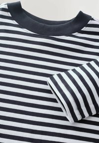 T-shirt i bomuld med striber, der har horisontale navy og hvide striber, en ribbet navy krave og korte ærmer. Blød tekstur og afslappet design.