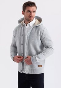 Felpa con cappuccio grigio chiaro realizzata in tessuto morbido, con zip frontale, rivestimento interno a contrasto e una patch con logo all'orlo.