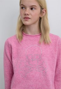 Pink sweater made of soft knit fabric featuring a silver rhinestone skull and crossbones design on the front. Round neckline, casual fit.