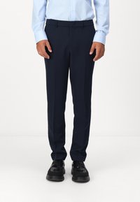 Die marineblauen Anzughosen zeichnen sich durch ein gerades Beinendes Design, glattes Material und einen dezenten Bügel aus. Sie werden mit einem hellblauen Hemd und schwarzen Schuhen getragen.