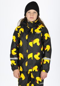 Schwarze wasserdichte Jacke mit einem wiederholten Muster aus gelben Gummienten, elastischen Bündchen und reflektierenden Akzenten. Dazu passende Hose.