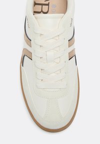Basket blanche avec des bandes latérales en suède beige, des lacets blancs et une semelle en gomme, vue de dessus.