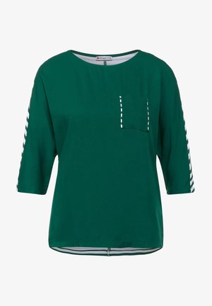 Top verde de manga corta con cuello redondo, que presenta un bolsillo en el pecho y detalles a rayas en las mangas. Textura suave y corte relajado.