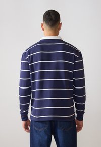 Navy blue long-sleeve polo shirt with white horizontal stripes and a white collar. Features soft fabric and a relaxed fit.
