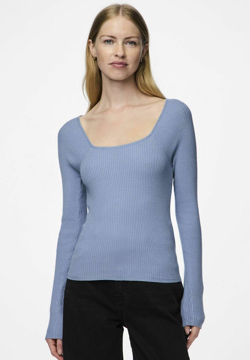 Šviesiai mėlyna ribota ilgomis rankovėmis palaidinė su kvadrato formos iškirpte ir prigludusia forma, su tekstūruotu audiniu ir šiek tiek išsiplėtusiomis rankovėmis.