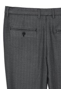 Pantaloni a motivo a treccia nera e bianca, con due tasche posteriori con bottoni e design frontale piatto. Realizzati in un tessuto testurizzato.