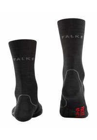 Calcetines negros hechos de tela texturizada, con un diseño de canalé, refuerzo en el talón y en la puntera, y un logo en el puño en color gris.