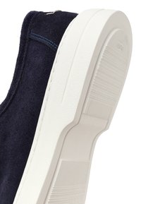 Navy blue suede shoe with white thick rubber sole, visible stitching, and textured grip on the bottom for traction.