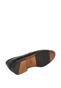 Schwarze Lederdressschuhe umgedreht, um die Sohle mit braunen und schwarzen Gummibereichen sowie der Hackett London Markierung zu zeigen.