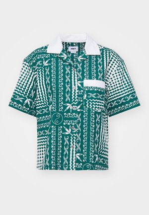Kortermet skjorte med et mønster i turkis og hvitt, som inneholder varierte geometriske former, en brystlomme og klassisk krage.