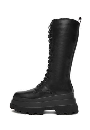 Schwarze, hohe Lederkampfstiefel mit klobiger Plateausohle und schnürbarem Vorderteil, seitliches Profil auf weißem Hintergrund.