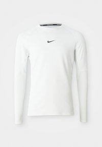 Langermet treningstrøye laget av hvitt stoff, med en svart Nike-logo på brystet og glatt, tettsittende design.