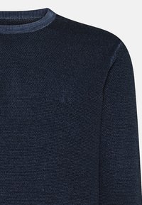 Maglione lavorato a maglia blu navy con scollo rotondo e orlo a costine. Presenta un delicato motivo testurizzato e un piccolo logo ricamato sul petto.