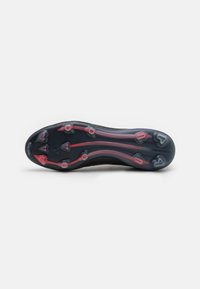 Sort atletiske skosåler med røde og pink detaljer, udstyret med flere nitter for traction og en tekstureret overflade for bedre greb.