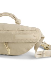 Bež bum bag s teksturiranom tkaninom, čvorastom užetom za držanje, prilagodljivim remenom i malim logotipom. Zatvaranje na zatvarač s ručicom.