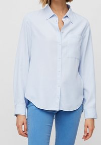 Camicia button-up azzurro chiaro con colletto, maniche lunghe, taschino sul petto e orlo curvo. Realizzata in un tessuto morbido.