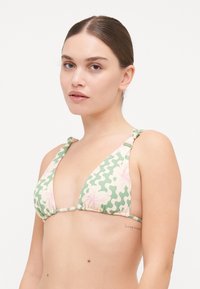 Triangelbikini i pastellgrön med vita vågor och rosa blommönster. Har justerbara knutband och en rynkad livrem. Slät textur.
