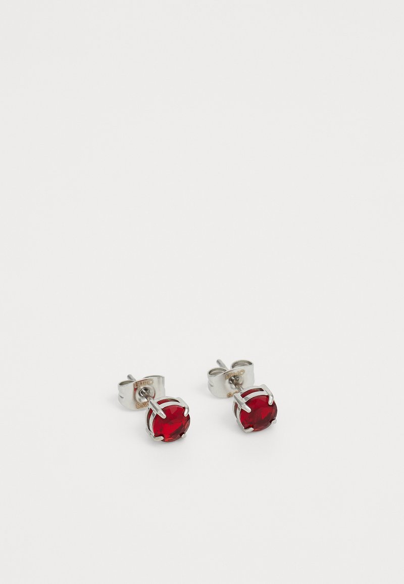 Pár stříbrných náušnic s kulatými červenými drahokamy uchycenými ve čtyřpřendových osazeních na bílém pozadí.