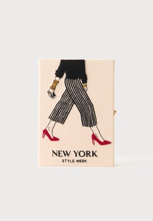 Frau trägt schwarzen Top, gestreifte weite Hose, rote Absätze und goldene Armbänder, läuft mit dem Text "New York Style Week" darunter.