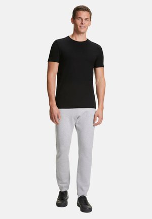 Maglietta nera a maniche corte abbinata a pantaloni sportivi grigio chiaro e scarpe da ginnastica nere. Design semplice, forma aderente e texture simile al cotone.