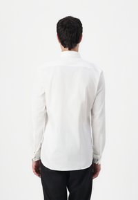 Witte overhemd met lange mouwen, een button-down kraag, rechte zoom en manchetknopen. Gladde textuur, getailleerd ontwerp en aangesloten silhouet.
