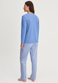 Hellblaues Longsleeve-Shirt mit Rundhalsausschnitt, kombiniert mit blauen und weißen gestreiften Pyjamahosen aus einem weichen Stoff, sichtbare Nähdetails.