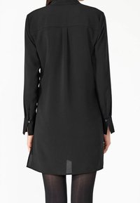 Czarna sukienka koszulowa z długim rękawem, wykonana z lekkiego materiału. Posiada kołnierzyk, mankiety zapinane na guziki oraz lekko zaokrąglony dół z rozcięciem z tyłu.