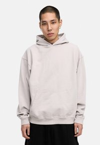 Helles graues Hoodie aus weichem Material. Verfügt über eine vordere Kängurutasche, weite Ärmel und eine Kapuze mit Kordelzug. Einfaches Design, lockere Passform.