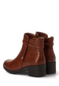 Botas de cuero marrón hasta el tobillo con una textura suave, puntera redondeada, tacón bajo cuadrado y detalle decorativo de correa atada.