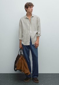 Hell gestreiftes Hemd mit Knöpfen, lockere blaue Jeans und dunkelbraune Schuhe. Hält eine braune Tasche und eine braune Jacke. Überall glatte Textur.