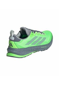 Chaussure de sport verte et grise avec tige en maille, surface texturée, trois bandes sur le côté et semelle intermédiaire grise mouchetée. Petite languette en relief à l'arrière.