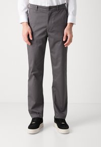 Grå dressbyxor i ett slätt tyg. Har en knäppning, sidofickor och en skräddarsydd passform. Bärs med svarta sneakers.