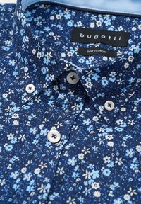 Blaues Blumenhemd aus weicher Baumwolle, mit navyfarbenem Hintergrund, hellblauen und weißen Blumen, spitzem Kragen und Kunststoffknöpfen.