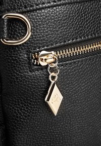 Borsa nera in pelle testurizzata con una cerniera dorata, un tirante argento e un charm a forma di diamante dorato con dettagli incisi.