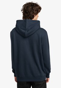 Navyblauwe hoodie met een trekkoord in de capuchon, met een relaxte pasvorm en ribbels bij de mouwen en onderkant. Gladde textuur, geen zichtbare patronen of logo's.